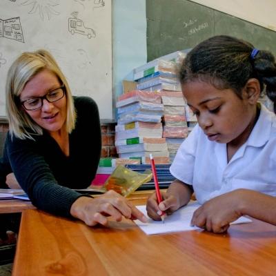 A Projects Abroad volunteer teaching in South Africa helps a young girl with her homework A student receives homework help from a volunteer working as a teacher in South Africa